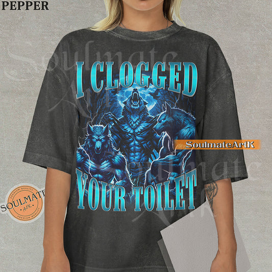Vintage-style graphic of three muscular blue wolves howling at the moon with bold metallic text reading I Clogged Your Toilet on a washed pepper Comfort Colors t-shirt.