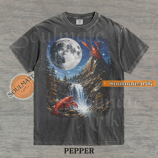 Graphic of crawfish on a mountain peak and by a waterfall under a giant full moon on a washed pepper shirt.