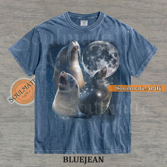 Collage of three sea lions in front of a glowing full moon and a starry night sky on a washed bluejean shirt.