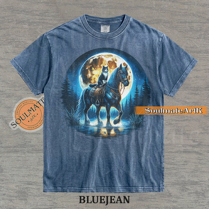 Detailed illustration of a cat sitting on a horse's saddle wading through a stream under a large full moon on a washed bluejean t-shirt.