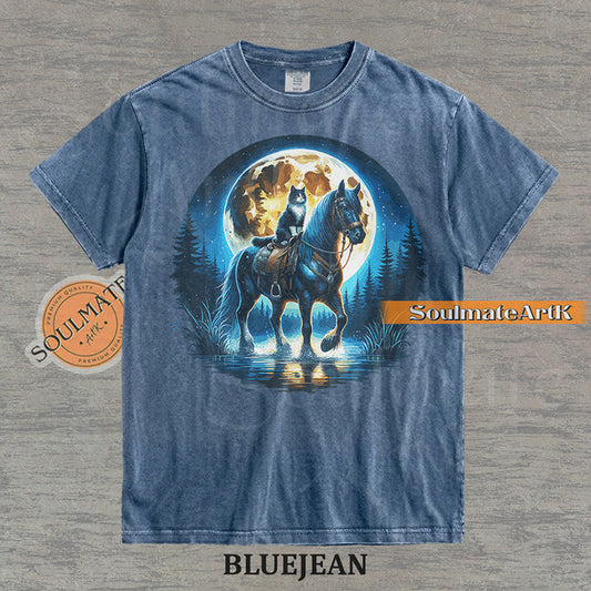 Detailed illustration of a cat sitting on a horse's saddle wading through a stream under a large full moon on a washed bluejean t-shirt.