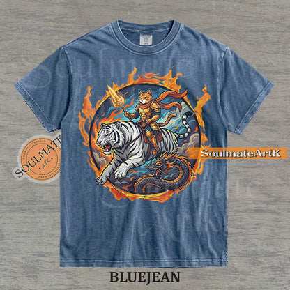 Illustration of an armored cat warrior riding a white tiger over a dragon, surrounded by a circle of fire on a washed bluejean shirt.