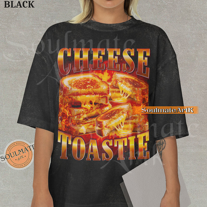 Graphic collage of melting grilled cheese sandwiches surrounded by flames with bold metallic text reading CHEESE TOASTIE on a washed black shirt.