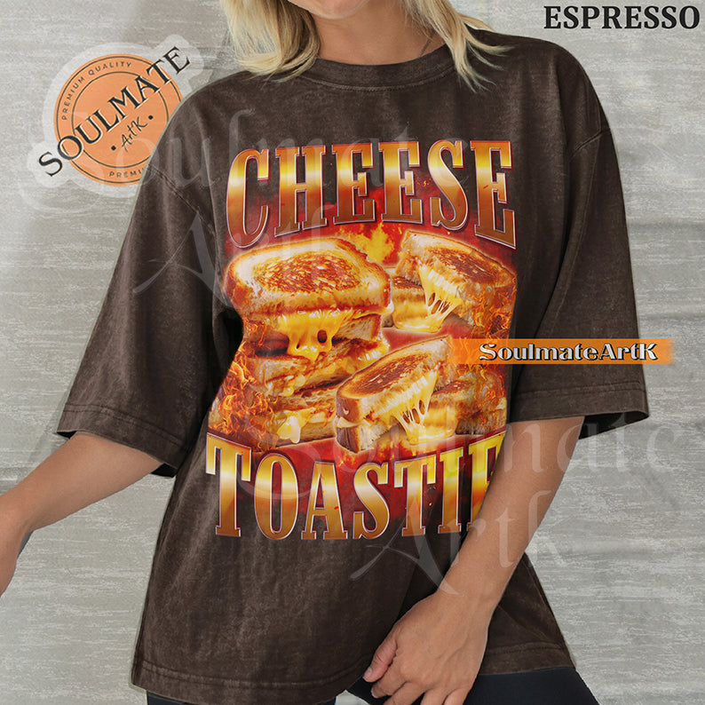 Graphic collage of melting grilled cheese sandwiches surrounded by flames with bold metallic text reading CHEESE TOASTIE on a washed espresso shirt.