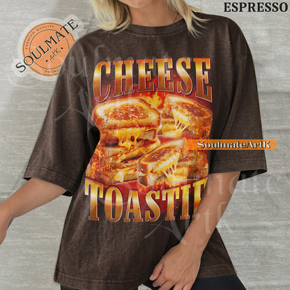 Graphic collage of melting grilled cheese sandwiches surrounded by flames with bold metallic text reading CHEESE TOASTIE on a washed espresso shirt.