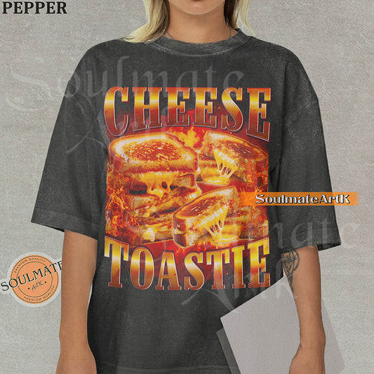 Graphic collage of melting grilled cheese sandwiches surrounded by flames with bold metallic text reading CHEESE TOASTIE on a washed pepper shirt.