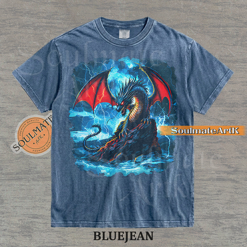 Vintage-style fantasy graphic of a black dragon with red wings perched on a rock amidst blue lightning and ocean waves on a washed bluejean t-shirt.