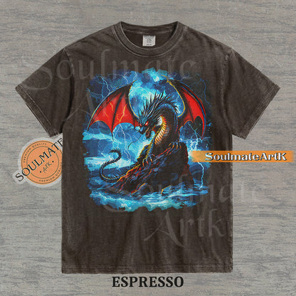 Vintage-style fantasy graphic of a black dragon with red wings perched on a rock amidst blue lightning and ocean waves on a washed espresso t-shirt.