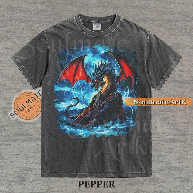 Vintage-style fantasy graphic of a black dragon with red wings perched on a rock amidst blue lightning and ocean waves on a washed pepper t-shirt.