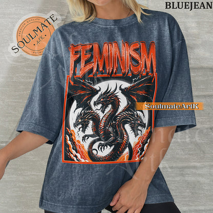 Illustration of a multi-headed red and black dragon in a framed graphic with bold red text reading Feminism on a washed bluejean shirt.