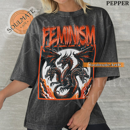 Illustration of a multi-headed red and black dragon in a framed graphic with bold red text reading Feminism on a washed pepper shirt.