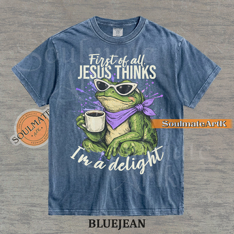Illustration of a green frog in sunglasses and a purple scarf holding a coffee mug with the text "First of all, Jesus thinks I'm a delight" on a washed bluejean shirt.