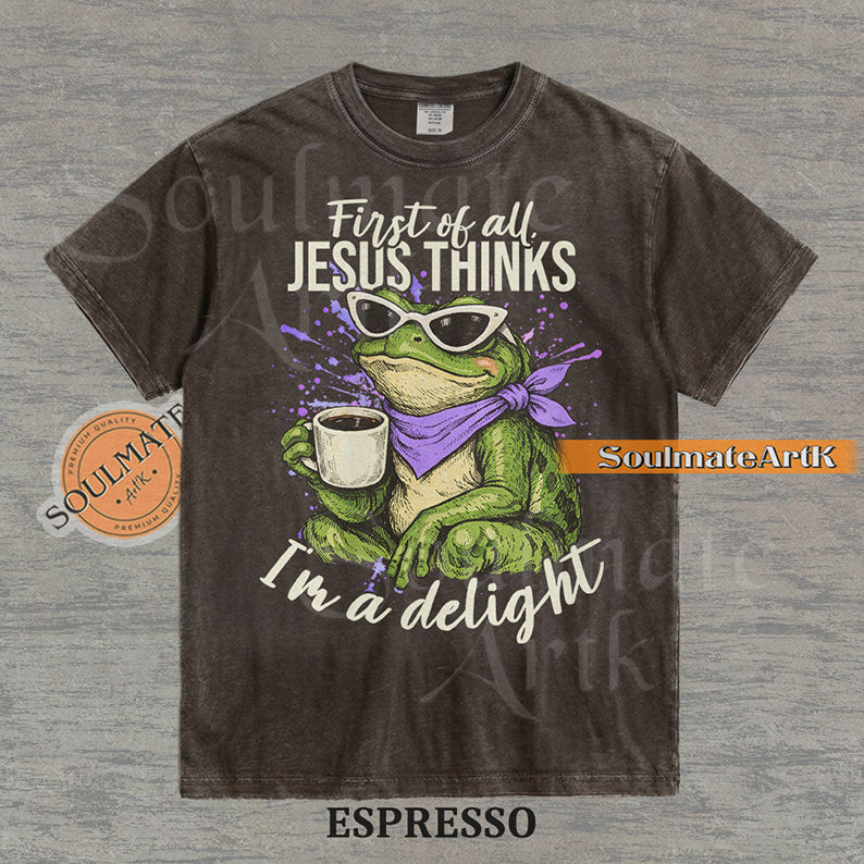 Illustration of a green frog in sunglasses and a purple scarf holding a coffee mug with the text "First of all, Jesus thinks I'm a delight" on a washed espresso shirt.