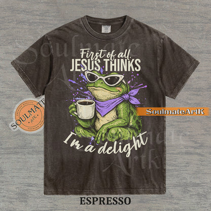 Illustration of a green frog in sunglasses and a purple scarf holding a coffee mug with the text "First of all, Jesus thinks I'm a delight" on a washed espresso shirt.