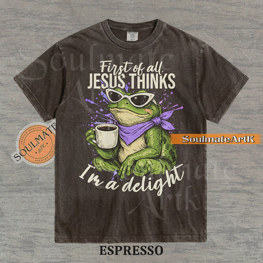Illustration of a green frog in sunglasses and a purple scarf holding a coffee mug with the text "First of all, Jesus thinks I'm a delight" on a washed espresso shirt.