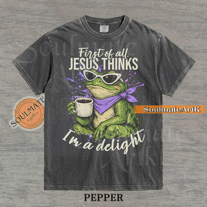 Illustration of a green frog in sunglasses and a purple scarf holding a coffee mug with the text "First of all, Jesus thinks I'm a delight" on a washed pepper shirt.