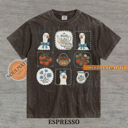 Cottagecore grid illustration featuring geese with bows, strawberries, tomatoes, and vintage teapots on a washed espresso t-shirt.