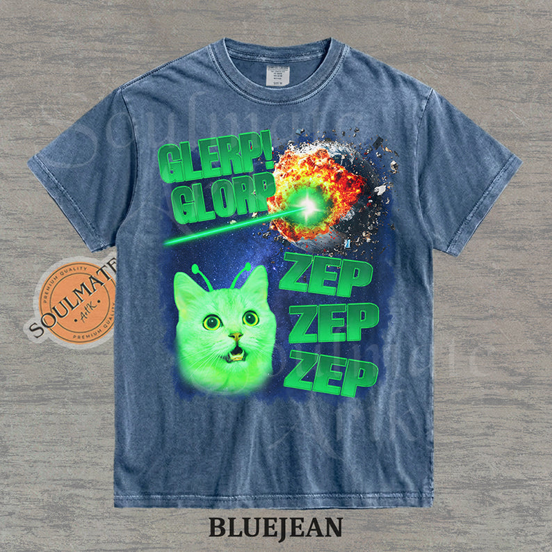 Graphic of a glowing green cat with antennae in space next to an exploding planet and text reading Glerp Glorp Zep Zep Zep on a washed bluejean shirt.