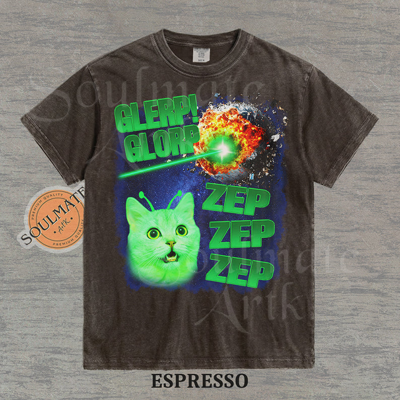 Graphic of a glowing green cat with antennae in space next to an exploding planet and text reading Glerp Glorp Zep Zep Zep on a washed espresso shirt.