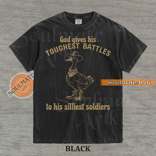 Vintage-style illustration of a goose wearing a cowboy hat, bandana, and boots with the text God gives his toughest battles to his silliest soldiers on a washed Comfort Colors t-shirt.