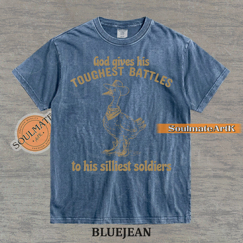 Vintage-style illustration of a goose wearing a cowboy hat, bandana, and boots with the text God gives his toughest battles to his silliest soldiers on a washed Comfort Colors t-shirt.