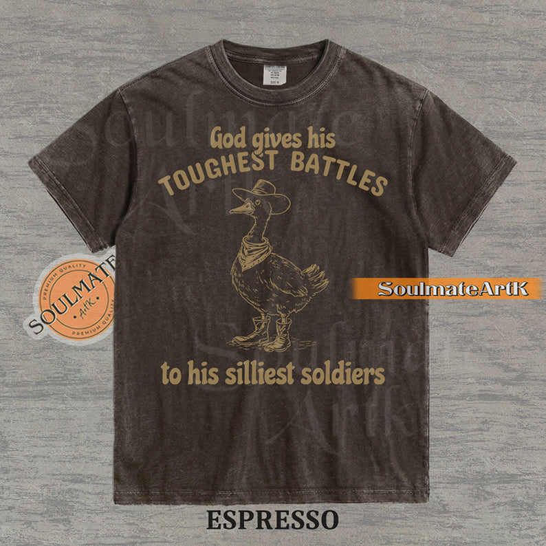 Vintage-style illustration of a goose wearing a cowboy hat, bandana, and boots with the text God gives his toughest battles to his silliest soldiers on a washed Comfort Colors t-shirt.