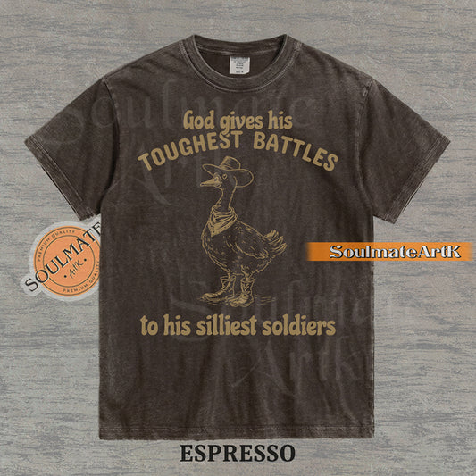 Vintage-style illustration of a goose wearing a cowboy hat, bandana, and boots with the text God gives his toughest battles to his silliest soldiers on a washed Comfort Colors t-shirt.