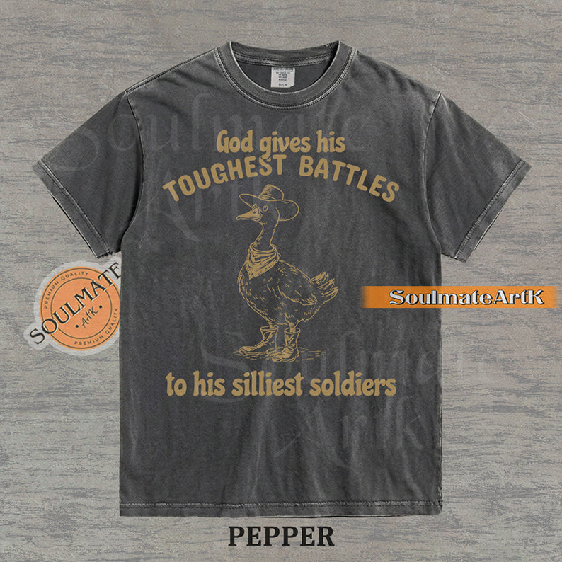 Vintage-style illustration of a goose wearing a cowboy hat, bandana, and boots with the text God gives his toughest battles to his silliest soldiers on a washed Comfort Colors t-shirt.