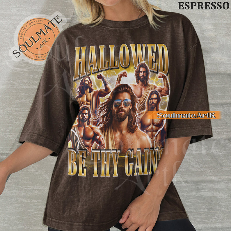 Vintage-style collage of a muscular man with a beard and sunglasses surrounded by lightning with bold gold metallic text reading Hallowed Be Thy Gains on a washed espresso t-shirt.