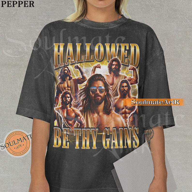 Vintage-style collage of a muscular man with a beard and sunglasses surrounded by lightning with bold gold metallic text reading Hallowed Be Thy Gains on a washed pepper t-shirt.