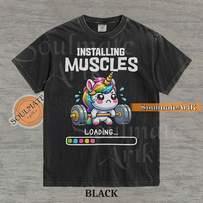 Cute cartoon unicorn lifting a heavy barbell with a loading bar and text reading Installing Muscles on a washed black shirt.