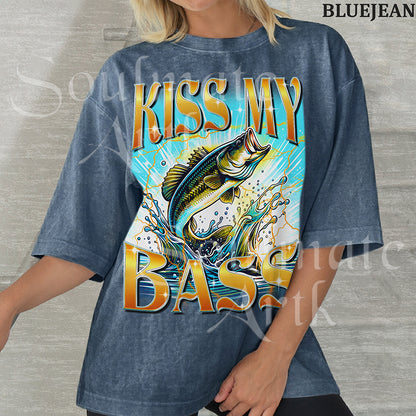 Graphic of a bass fish leaping out of water with golden lightning and bold text reading KISS MY BASS on a washed bluejean shirt.