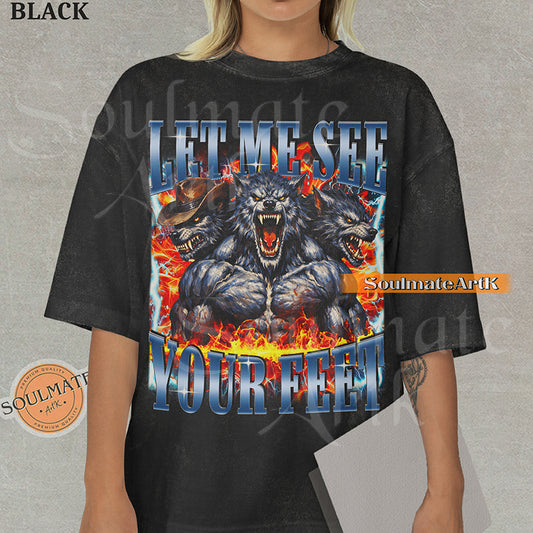 Graphic of three muscular werewolves surrounded by fire and lightning with bold blue text reading LET ME SEE YOUR FEET on a washed black shirt.