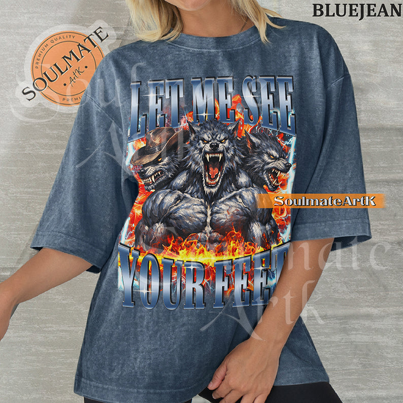 Graphic of three muscular werewolves surrounded by fire and lightning with bold blue text reading LET ME SEE YOUR FEET on a washed bluejean shirt.