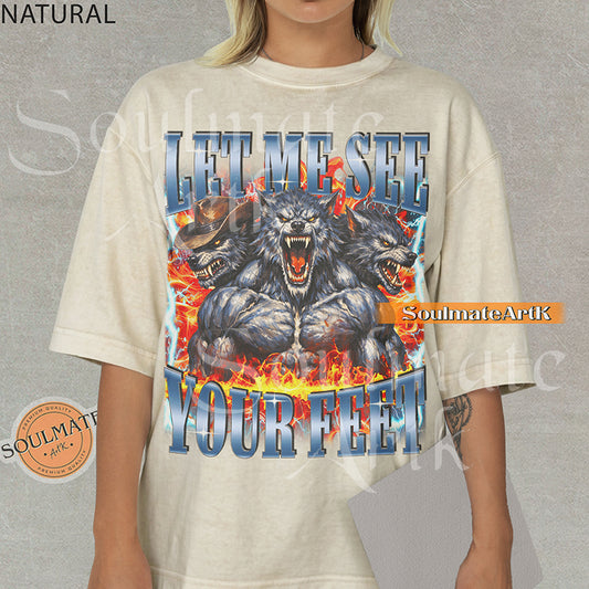 Graphic of three muscular werewolves surrounded by fire and lightning with bold blue text reading LET ME SEE YOUR FEET on a natural/ivory shirt.