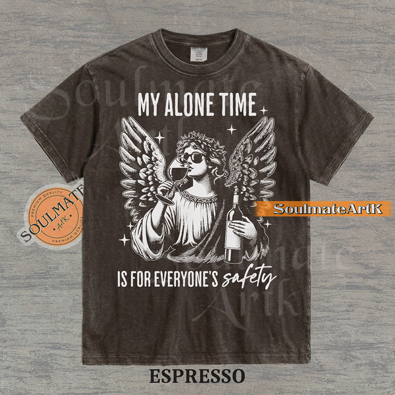 Vintage-style engraving of an angel wearing sunglasses and holding a wine bottle/glass with text reading My Alone Time Is For Everyone's Safety on a washed espresso t-shirt.