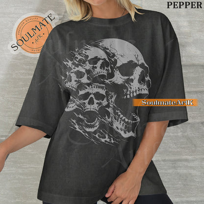 Graphic featuring three detailed screaming skulls in a monochrome illustrative style on a washed pepper t-shirt.