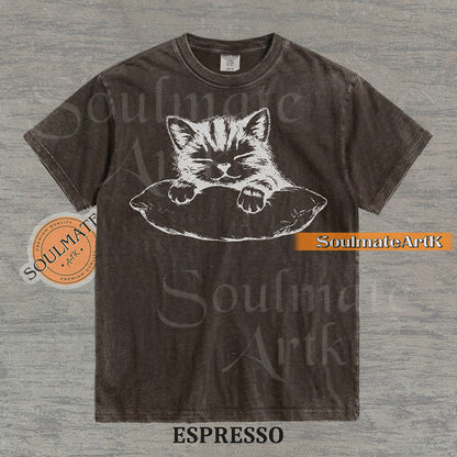Hand-drawn sketch of a striped kitten sleeping on a pillow in black ink on a espresso vintage-wash t-shirt.