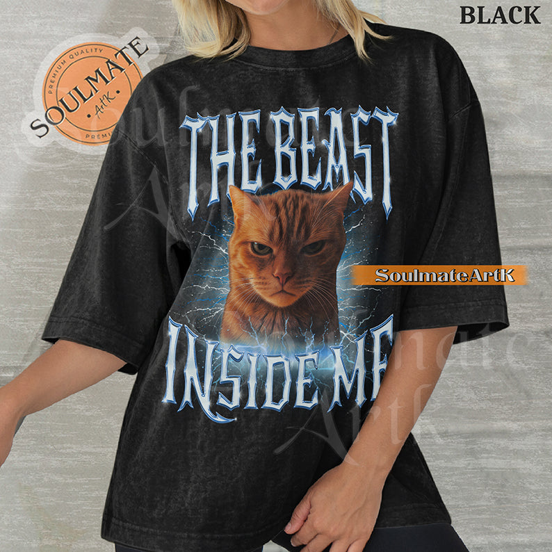 Graphic of an intense orange cat surrounded by blue lightning with bold metallic text reading THE BEAST INSIDE ME on a washed black shirt.