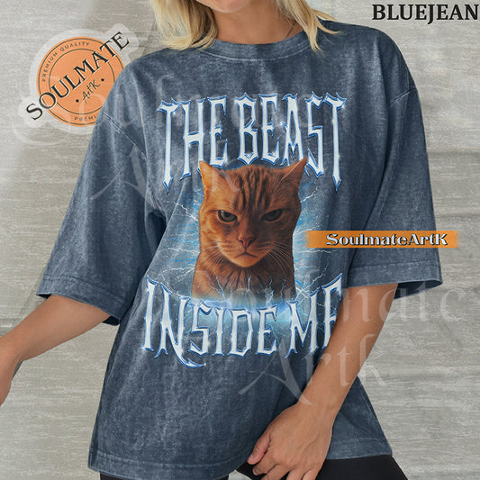 Graphic of an intense orange cat surrounded by blue lightning with bold metallic text reading THE BEAST INSIDE ME on a washed bluejean shirt.