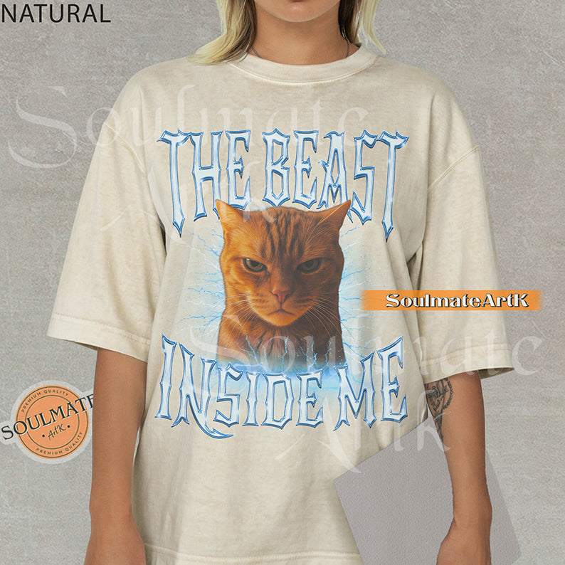 Graphic of an intense orange cat surrounded by blue lightning with bold metallic text reading THE BEAST INSIDE ME on a natural/ivory shirt.