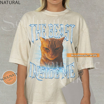 Graphic of an intense orange cat surrounded by blue lightning with bold metallic text reading THE BEAST INSIDE ME on a natural/ivory shirt.