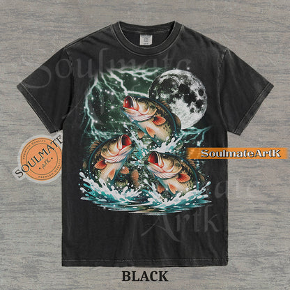 Collage of three bass fish jumping out of water in front of a glowing moon and lightning on a washed black shirt.