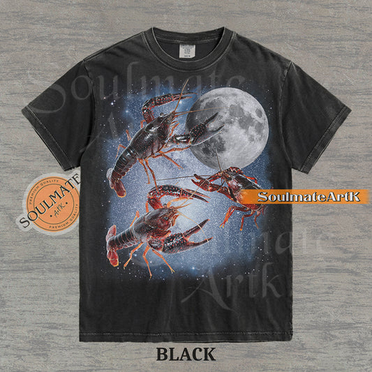 Graphic of three crawfish floating in a starry space nebula next to a full moon on a washed black shirt.