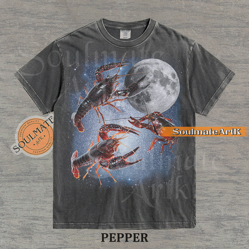 Graphic of three crawfish floating in a starry space nebula next to a full moon on a washed pepper shirt.