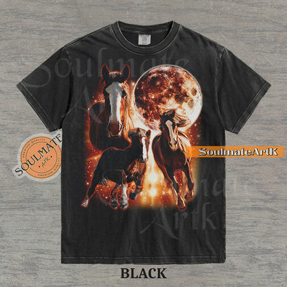 Epic celestial graphic of three horses galloping in front of a giant fiery moon and orange stardust on a washed Black Comfort Colors t-shirt.