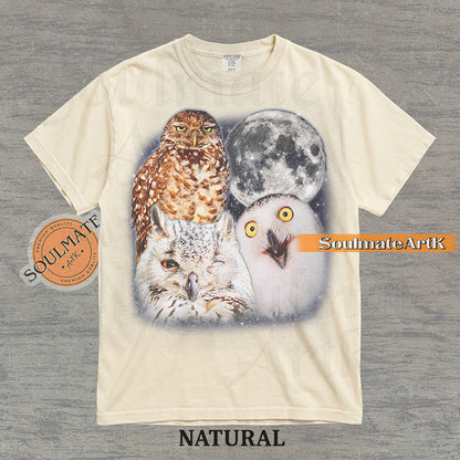 Detailed nature graphic of three different owls next to a large full moon in a starry night sky on a natural t-shirt.