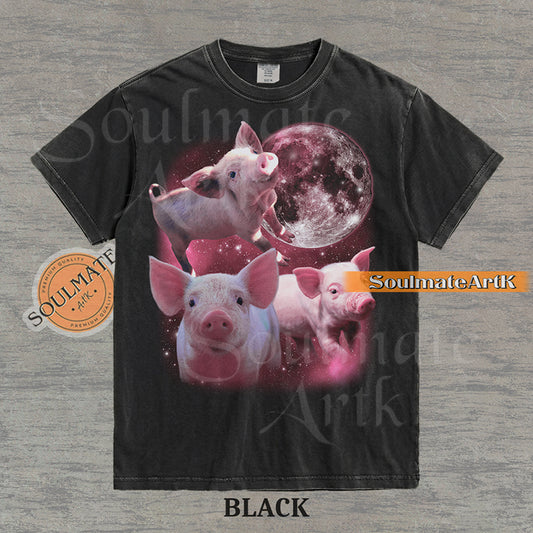 Collage of three pink piglets in front of a glowing pink moon and a starry nebula on a washed black shirt.