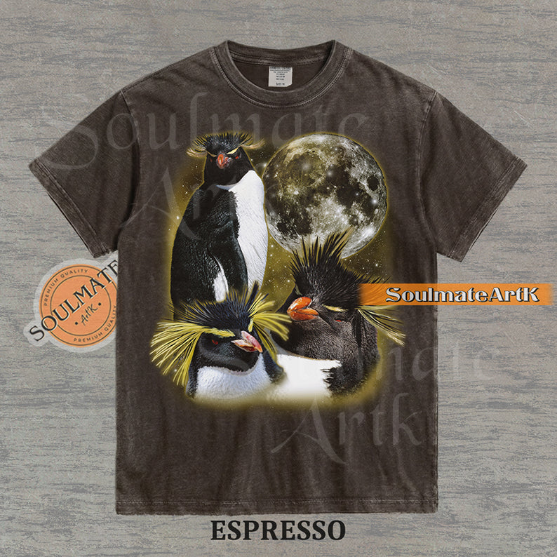 Collage of three Rockhopper penguins with yellow crests in front of a glowing moon and a golden starry nebula on a washed espresso shirt.