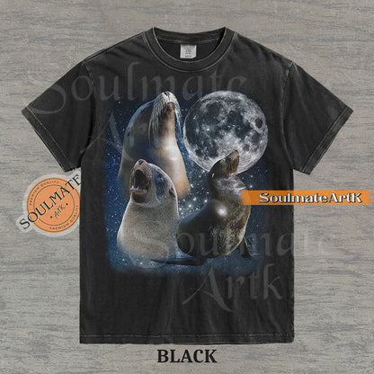 Collage of three sea lions in front of a glowing full moon and a starry night sky on a washed black shirt.